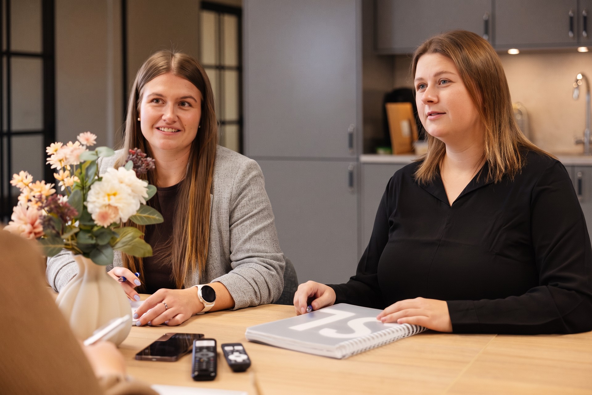 Sandra och Sanna i samtal vid bordet på kontoret